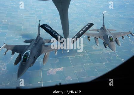 Zwei Kampffalken der US Air Force F-16 des 180. Fighter Wing der Ohio Air National Guard fliegen hinter einem US Air Force KC-135 Stratotanker des 185. Air National Guard Air Betanking Wings über Iowa, 11. August 2022. Die F-16s und KC-135 waren auf dem Weg zum Baseballspiel der Field of Dreams Major League, um während des Spiels der US-Nationalhymne einen Überflug durchzuführen. (USA Foto der Air National Guard von Airman 1. Class Tylon Chapman) Stockfoto