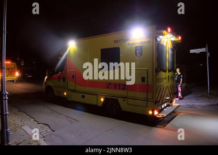 Berlin, Deutschland. 12. August 2022. Ein Notarztwagen der Bundeswehr steht mit anderen Einsatzfahrzeugen auf einer Straße in Grunewald. Gemeinsam mit der Bundeswehr und dem Robert Koch-Institut untersucht die Polizei im Berliner Bezirk Grunewald einen vermuteten Sprengsatz oder Agenten in einem Wohngebäude. Eine Polizeisprecherin sagte am späten Freitagabend. Sie suchen nach explosiven oder biologischen Materialien. Quelle: Paul Zinken/dpa/Alamy Live News Stockfoto