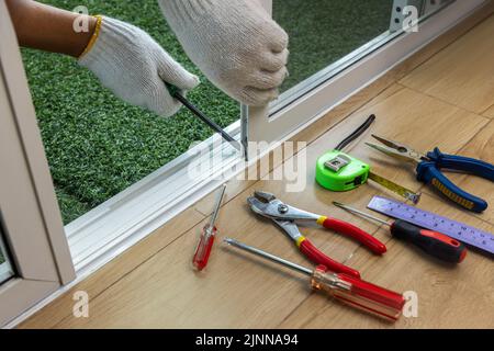 Arbeiter, der die Schiebetür des Insektenschutzschirms fixiert Stockfoto