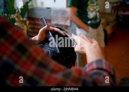 Scheren schneiden dem jungen Mann die Haare Stockfoto
