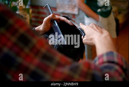 Nahaufnahme der Schere Schnitt dem jungen Mann die Haare Stockfoto