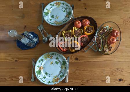 Gefüllte Paprika und Tomaten in zwei Aufläufen auf dem Esstisch, Bayern, Deutschland Stockfoto