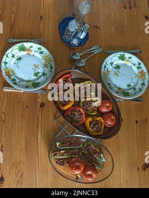 Gefüllte Paprika und Tomaten in zwei Aufläufen auf dem Esstisch, Bayern, Deutschland Stockfoto