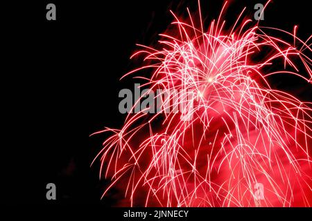 Silvesterfeuerwerk und ein Frohes neues Jahr. Freigesetzte Feuerwerkblumen vor schwarzem Hintergrund Stockfoto