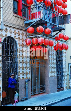 Eine ältere Frau mit verbundenen Augen steht im Rahmen eines religiösen Rituals am Eingang des Taoistischen Tempels von Ma Tsu in Chinatown, San Francisco Stockfoto