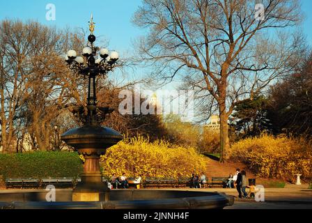 Eine Mutter und ein Kind gehen an einem frühen Frühlingstag um den reich verzierten Brunnen im Cherry Hill-Teil des New Yorker Central Park Stockfoto