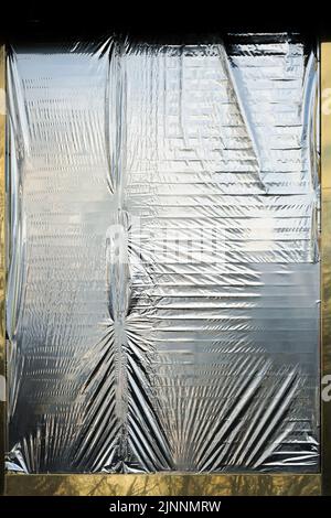 Verknitterte Folienfolie, die das Fenster nicht fest verdeckt Stockfoto