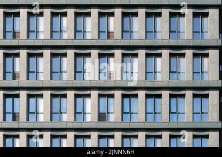Fragment der gemeinsamen Gebäudefassade mit Fenstern, die den Himmel reflektieren Stockfoto