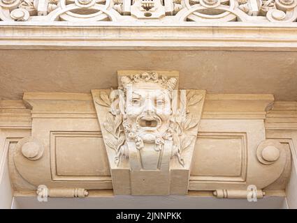 Nahaufnahme eines steinernen menschlichen Gesichts als Dekor oder Mascaron auf der Facad des Gebäudes Stockfoto