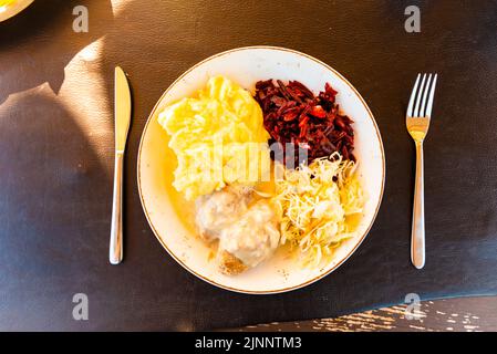 Hausgemachte Fleischschnitzel mit Kartoffelpüree und Gemüsesalat auf einem Teller auf einem grauen Tisch.Draufsicht, Nahaufnahme. Stockfoto