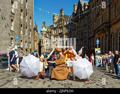 Edinburgh, Schottland, 11. August 2022 Festival Fringe Royal Mile Schauspieler der Gruppe The Clowns Station konstruieren aus ihren Schirmen ein vorgetäuschter Wagen Stockfoto