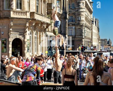 Edinburgh, Schottland, 11. August 2022 die Zuschauer des Festival Fringe Royal Mile beobachten den Balanceakt mit einem jungen Mann, der eine junge Dame mit erhobenen Armen unterstützt Stockfoto