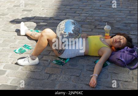 Edinburgh, Schottland, 11. August 2022 Festival Fringe in der Royal Mile unterwegs liegend eine junge Dame, die aus dem Stück Tod einer Disco-Tänzerin spielt Stockfoto