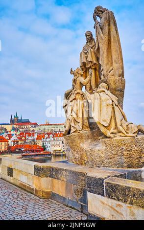 Die steinerne Statue des hl. Kyrill und Methodius auf der Karlsbrücke gegenüber der Prager Burg mit der St.-Veits-Kathedrale, die die Skyline dominiert, Prag, Tschechien Stockfoto