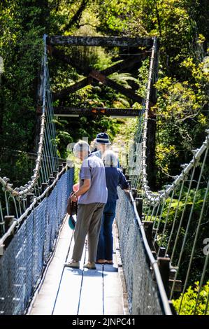 Besucher auf der Schaukelbrücke über die Hokitka Gorge im Regenwald an der Westküste auf South Island in Neuseeland Stockfoto