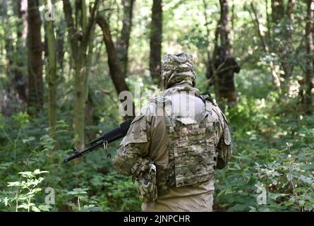 Soldaten mit Sturmgewehr im Wald. Soldaten im Kampf. Taktische Übungen. Krieg in der Ukraine Stockfoto