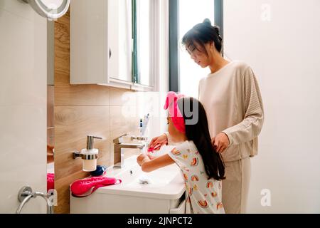 Asiatische Mädchen putzen ihre Zähne mit Mutter im Badezimmer zu Hause Stockfoto