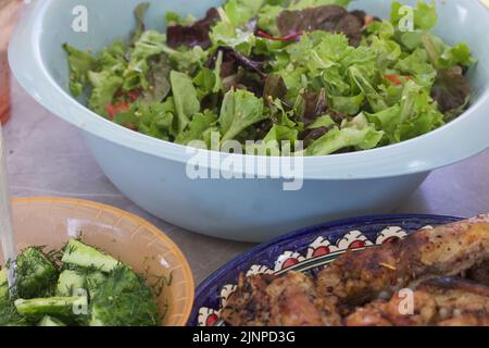 Gegrilltes Fleisch. Liegt in einer Schüssel. Gemüse und Kräuter in der Nähe. Stockfoto