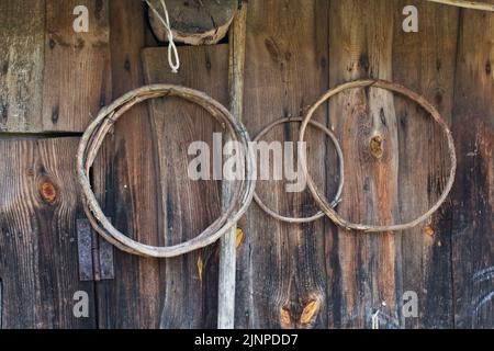 Haushaltsvorräte an der Wand einer alten Scheune aus Brettern. Äußere Details. Nahaufnahme. Stockfoto