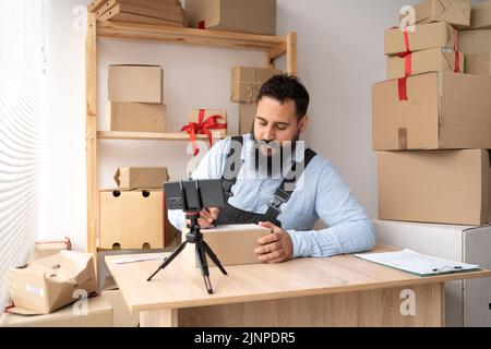 Startup indian Mann Unternehmer glücklich nach neuen Auftrag von Kunden mit Smartphone, Handy und Lieferbox auf dem Tisch, Kleinunternehmer Stockfoto