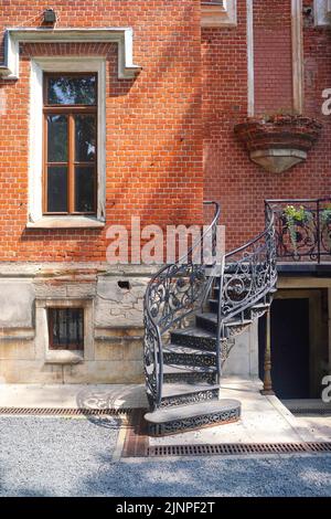 Der Blumentopf hängt unter dem Dach an der roten Wand. Hochwertige Fotos Stockfoto