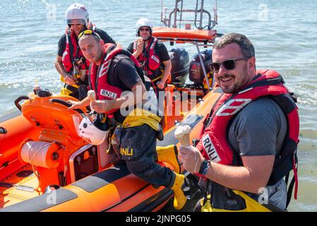 Southend on Sea, Essex, Großbritannien. 13. August 2022. Das heiße Wetter hat sich in der neuen Stadt Southend on Sea fortgesetzt, und viele Menschen fahren zum Resort, um sich am Meer abzukühlen. Die lokale RNLI Lifeboat Crew machte eine Pause von ihrer Küstenstreife, um sich etwas kühlendes Eis zu holen Stockfoto