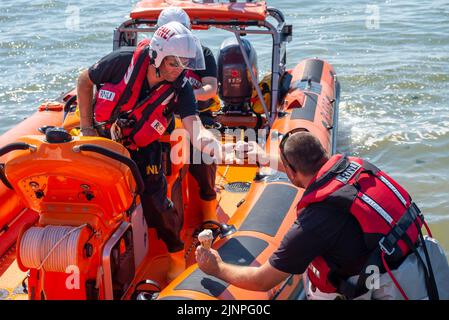 Southend on Sea, Essex, Großbritannien. 13. August 2022. Das heiße Wetter hat sich in der neuen Stadt Southend on Sea fortgesetzt, und viele Menschen fahren zum Resort, um sich am Meer abzukühlen. Die lokale RNLI Lifeboat Crew machte eine Pause von ihrer Küstenstreife, um sich etwas kühlendes Eis zu holen Stockfoto