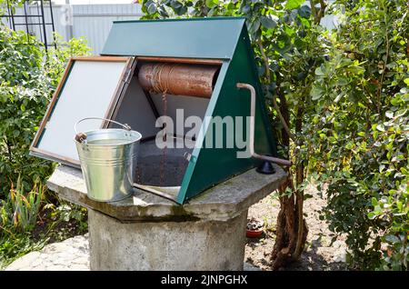 Alte Ziehbrunnen im europäischen Dorf. Retro Steinwasserbrunnen in ländlicher Umgebung Stockfoto