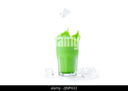 Matcha Grüner Tee Latte in einem Glas auf weißem Hintergrund, isoliert. Eiswürfel fallen in ein Glas mit Matcha-Latte-Kaffee. Spritzer aus den Eiswürfeln. Stockfoto