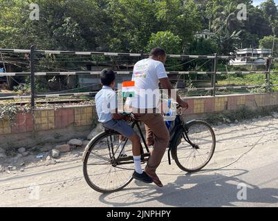 Guwahati, Assam, Indien. 13. August 2022. Ein Nachbau der indischen Nationalflagge wird von einem jungen Studenten mit seinen Eltern genommen. Der 75.. Jahrestag der indischen Unabhängigkeit, oder Azadi Ka Amrit Mahotsav, wird am 15. 2022. August gefeiert. Um Indiens 75.-jähriges Jubiläum zu feiern, wurde unter der Schirmherrschaft von Azadi Ka Amrit Mahotsav eine Kampagne namens „'Har Ghar Tiranga'“ gestartet. Die Kampagne ermutigt die Menschen, die Tiranga (dreifarbig, indische Nationalflagge) zu Hause zu hissen. Für jeden Indianer steht die dreifarbige Flagge für Stolz. Als Symbol der nationalen Integrität repräsentiert sie die Hoffnungen und Bestrebungen von Stockfoto