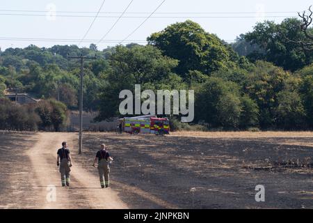 Hedgerley, Buckinghamshire, Großbritannien. 13.. August 2022. Feuerwehrleute des Feuerwehr- und Rettungsdienstes Buckinghamshire waren heute wieder dabei, schwelende Hotspots am Schauplatz eines riesigen Feldfeuers in Hedgerley, Buckinghamshire, zu löschen. Gestern wurden bei einem schweren Brand, der sich auf den Damm von M40 ausbreitete, etwa 25 Hektar Ackerland zerstört. Als der Rauch über die M40 driftete, wurden zwei Spuren der M40 in Richtung Norden zwischen Junction 1A (Kreuzung M25) und Junction 2 (Beaconsfield) geschlossen. Quelle: Maureen McLean/Alamy Live News Stockfoto