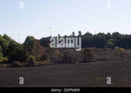 Hedgerley, Buckinghamshire, Großbritannien. 13.. August 2022. Feuerwehrleute des Feuerwehr- und Rettungsdienstes Buckinghamshire waren heute wieder dabei, schwelende Hotspots am Schauplatz eines riesigen Feldfeuers in Hedgerley, Buckinghamshire, zu löschen. Gestern wurden bei einem schweren Brand, der sich auf den Damm von M40 ausbreitete, etwa 25 Hektar Ackerland zerstört. Als der Rauch über die M40 driftete, wurden zwei Spuren der M40 in Richtung Norden zwischen Junction 1A (Kreuzung M25) und Junction 2 (Beaconsfield) geschlossen. Quelle: Maureen McLean/Alamy Live News Stockfoto