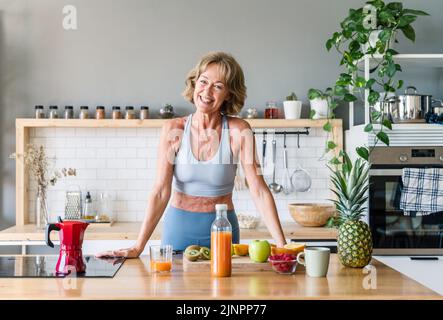 Schöne reife ältere Frau zu Hause, häusliches Leben und Freizeit Momente - 50-60 Jahre alt hübsche weibliche Erwachsene tragen Sportbekleidung essen gesunde Lebensmittel Stockfoto