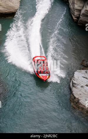 Die Besucher genießen den Nervenkitzel mit hoher Geschwindigkeit auf einem Shotover-Jet-Flachbodenboot, das mit zwei 350 Mercruiser V8-Motoren angetrieben wird und ein kombiniertes 700-Pferd produziert Stockfoto