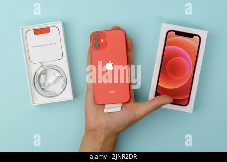 Tjumen, Russland-18. Juli 2022: Apple iPhone 12 mini mit Retail-Box, rote Farbe auf blauem Hintergrund Stockfoto