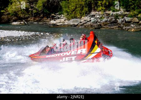 Besucher genießen den Nervenkitzel mit hoher Geschwindigkeit auf einem Shotover Jet-Flachbodenboot, das mit zwei 350 Mercruiser V8-Motoren angetrieben wird und ein kombiniertes 700-Pferd produziert Stockfoto