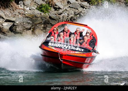 Besucher genießen den Nervenkitzel mit hoher Geschwindigkeit auf einem Shotover Jet-Flachbodenboot, das mit zwei 350 Mercruiser V8-Motoren angetrieben wird und ein kombiniertes 700-Pferd produziert Stockfoto