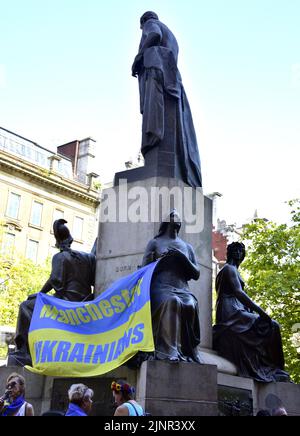 Manchester, Großbritannien, 13.. August 2022. Ein „Manchester Ukrainians“-Banner auf den Bronzefiguren auf der Statue des Herzogs von Wellington. „Manchester steht mit der Ukraine“, eine Anti-Kriegs-Kundgebung, ein Protest gegen die russische Invasion der Ukraine, in Piccadilly Gardens, im Zentrum von Manchester, England, Vereinigtes Königreich. Die Proteste werden vom Ukrainischen Kulturzentrum, Manchester, organisiert. An diesem Samstag, dem 25.., wurde dieser Protest abgehalten, um die Aufmerksamkeit auf den anhaltenden Krieg zu lenken und um Unterstützung für die Ukraine zu suchen. Quelle: Terry Waller/Alamy Live News Stockfoto