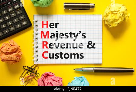 HMRC her majestys Einkommens- und Zollsymbol. Konzeptworte HMRC her majestys Einnahmen und Bräuche auf weißer Note auf schönem gelben Hintergrund. Bus Stockfoto