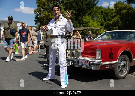 Bad Nauheim, Deutschland. 13. August 2022. Beim European Elvis Festival steht ein Elvis-Imitator vor einem Oldtimer. Das Festival findet in diesem Jahr zum 20.. Mal in Bad Nauheim statt. Presley war von Oktober 1958 bis März 1960 als Soldat in Friedberg stationiert und lebte in Bad Nauheim. Quelle: Hannes P. Albert/dpa/Alamy Live News Stockfoto