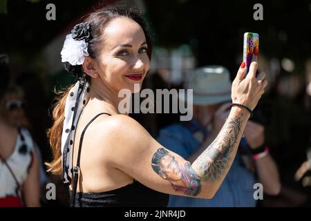 Bad Nauheim, Deutschland. 13. August 2022. Eine Besucherin trägt ein Elvis-Tattoo auf ihrem Arm beim European Elvis Festival. Das Festival findet in diesem Jahr zum 20.. Mal in Bad Nauheim statt. Presley war von Oktober 1958 bis März 1960 als Soldat in Friedberg stationiert und lebte in Bad Nauheim. Quelle: Hannes P. Albert/dpa/Alamy Live News Stockfoto