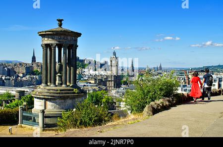 EDINBURGH SCHOTTLAND CALTON HILL DAS DUGALD STEWART MEMORIAL UND ZWEI PERSONEN BLICKEN AN EINEM HEISSEN SOMMERTAG AUF DIE STADT Stockfoto