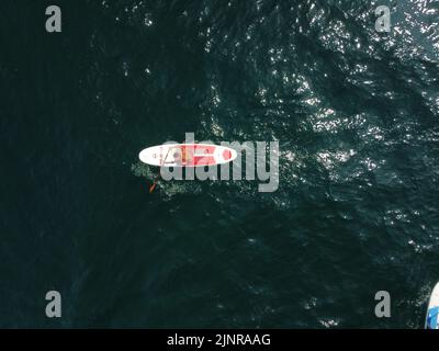 Seemann sup. Blick von oben auf den Mann, der im Meer schwimmt, und Paddeltouren bei Sonnenuntergang im Sommer. Gesunde starke männliche genießen im Freien aktiven Lebensstil und Stockfoto