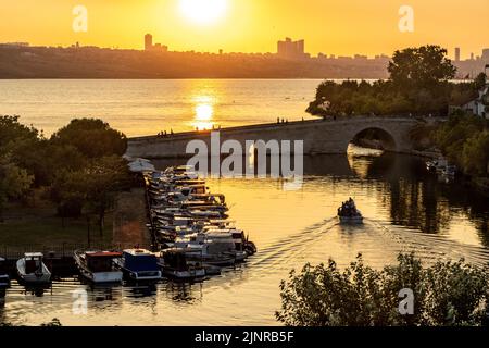 Kucukcekmece, Istanbul, Türkei - Juni 29 2022: Steinbrücke und Fischerboote am See im Stadtteil Kucukcekmece in Istanbul. Bei Sonnenuntergang Stockfoto
