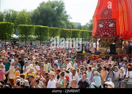 Moskau, Russland. 13. vom August 2022. Die Menge der Anhänger marschiert mit dem Hauptwagen während der Feier der Hare Krishna Ratha Yatra Parade oder des Hindu Religious Chariot Festivals, als Teil des India Day Festivals im Dream Island Park, Russland Stockfoto