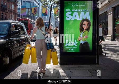 Eine Shopper-Frau trägt am 12.. August 2022 in London, England, eine Handvoll Sefridges Einkaufstaschen in Richtung eines schwarzen Taxis auf der Oxford Street im West End. Nachdem die Bank of England die Zinssätze auf 1,75 % angehoben hat, besteht die Gewissheit, dass sich Großbritannien bis zum vierten Quartal 2022 in einer Rezession befinden und die Inflation weiter steigen wird. Stockfoto