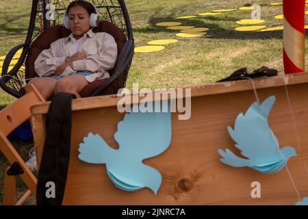 Moskau, Russland. 13. August 2022. Ein Mädchen entspannt sich in einem Stuhl am Ort des India Day Festivals im Dream Island Park in Moskau, Russland Stockfoto