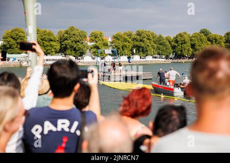 Hannover, Deutschland. 13. August 2022. Zuschauer beobachten das karitative Entenrennen am Nordufer des Maschsee. Das Entenrennen 11. auf dem Maschsee wird vom NKR (NKR) organisiert und findet am vorletzten Tag des Maschsee-Festivals statt. Kredit: Michael Matthey/dpa/Alamy Live Nachrichten Stockfoto