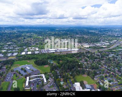 Schießen von einer Drohne. Eine kleine grüne Stadt, ein Vorort mit ausgebauter Infrastruktur. Dächer von einstöckigen Häusern, gepflasterte Straßen. Eine Bergkette ist sichtbar Stockfoto