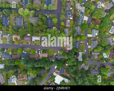 Blick von oben auf eine kleine grüne Stadt. Dächer einstöckiger Gebäude, gepflasterte Straßen, grüne Bäume, Sträucher, Rasenflächen. Karte, Infrastruktur, Umweltschutz, Stockfoto